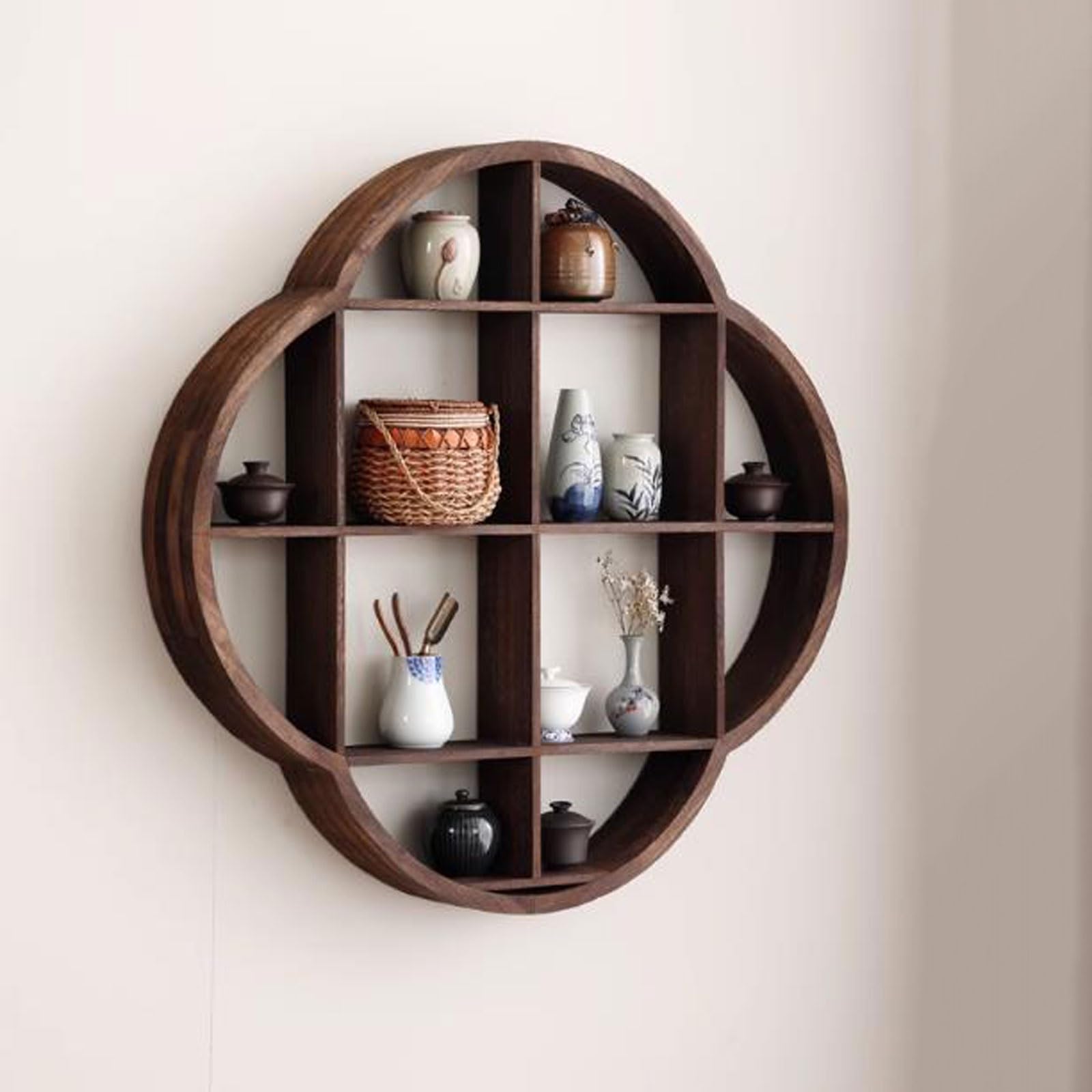 A wall-mounted wooden display shelf with a unique circular and petal-shaped design, featuring multiple compartments holding various decorative items such as vases, teapots, a woven basket, and small ornaments. The shelf's rustic and elegant look adds a touch of traditional and artistic flair, perfect for showcasing items in a home or office setting.