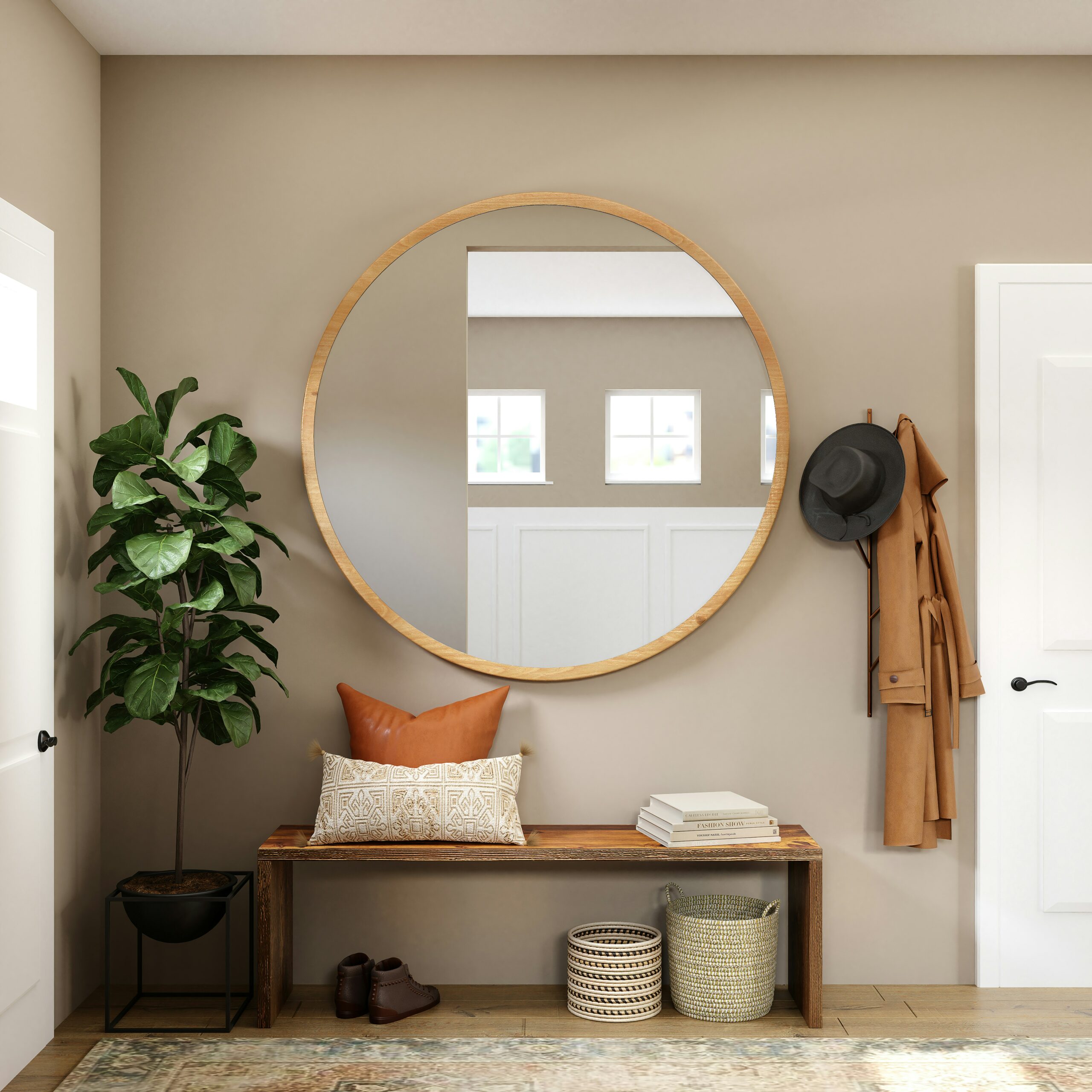 A stylish entryway featuring a large round mirror with a light wooden frame mounted on a beige wall. Below the mirror is a wooden bench with decorative pillows in earthy tones. To the right, a coat and hat are hung on the wall. A green plant in a black planter adds a touch of nature, and baskets are placed under the bench for storage. Natural light flows into the room through windows reflected in the feng shui mirror.